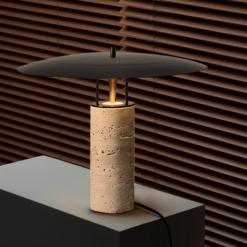 Travertine table lamp with black floating saucer shade in warm interior