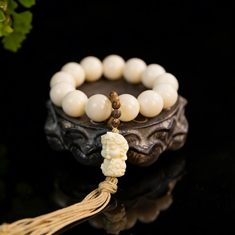 White Jade Bodhi-style hand mala with Dumu-style focal carving and long tassel in a lifestyle setting