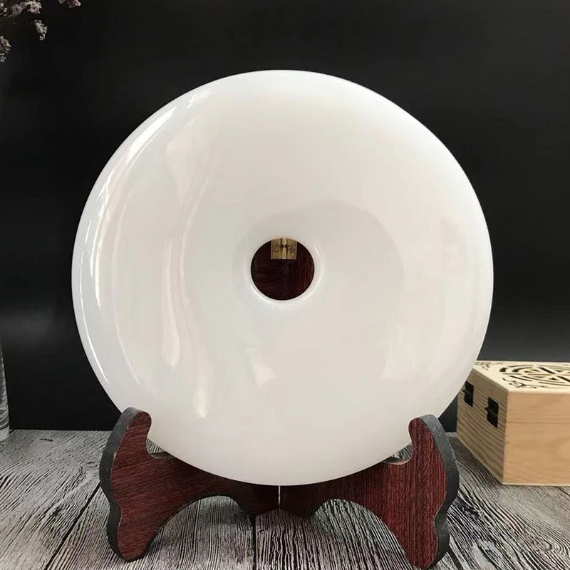 Polished white Chinese peace buckle disc ornament on dark wood stand