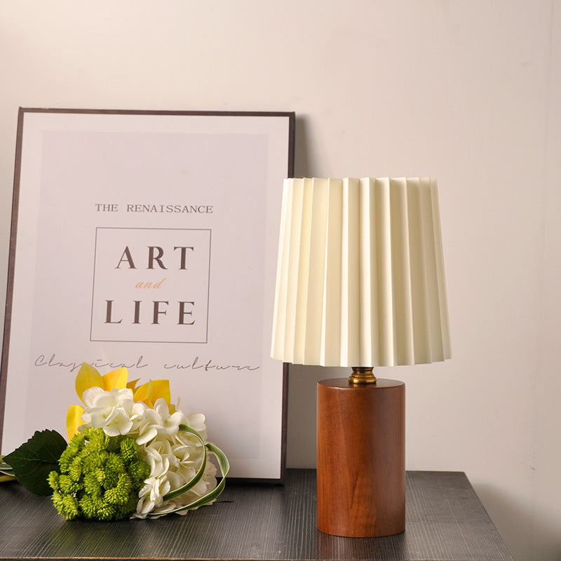 Natural wood cylinder pleated lamp styled with flowers and framed art