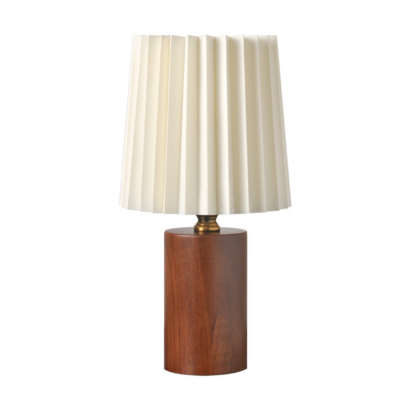 Walnut wood cylinder table lamp with cream pleated shade on white background