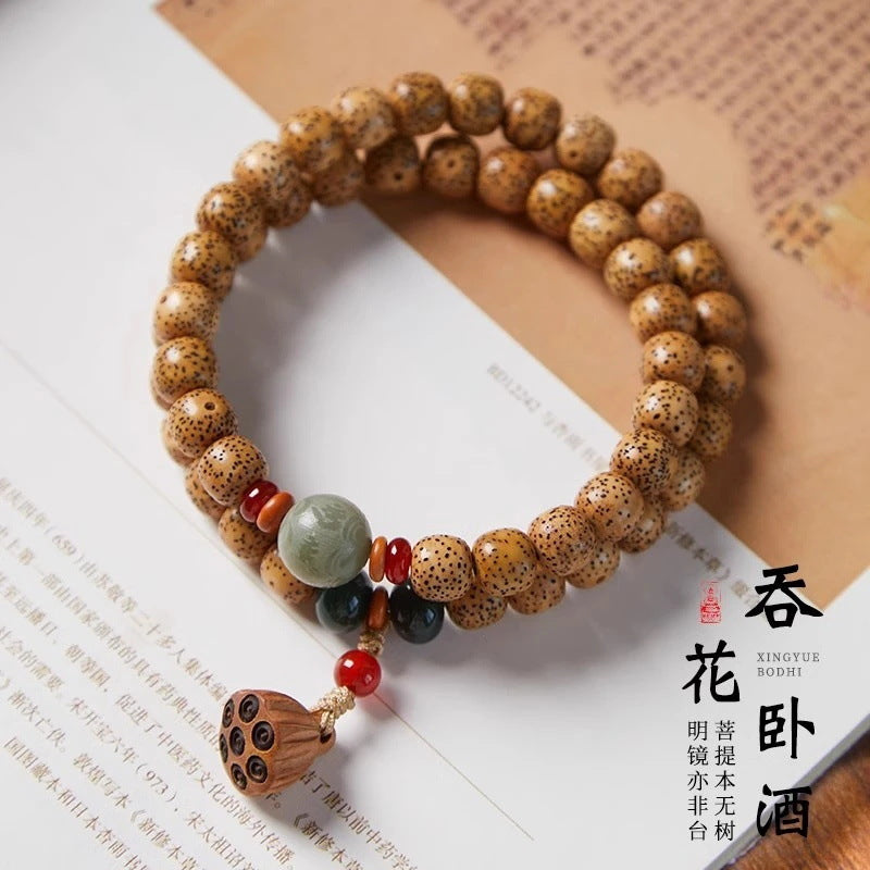 Golden Xingyue Bodhi double-wrap bracelet with jade-tone center bead, dark green accents and carved tassel