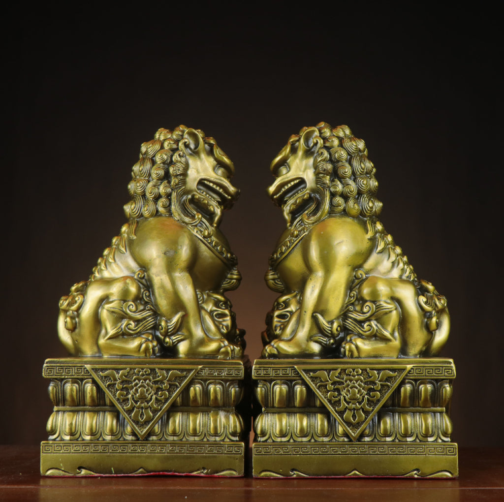 Side view of yellow brass Beijing palace guardian lion pair on lotus-style bases with traditional Chinese door-lion styling