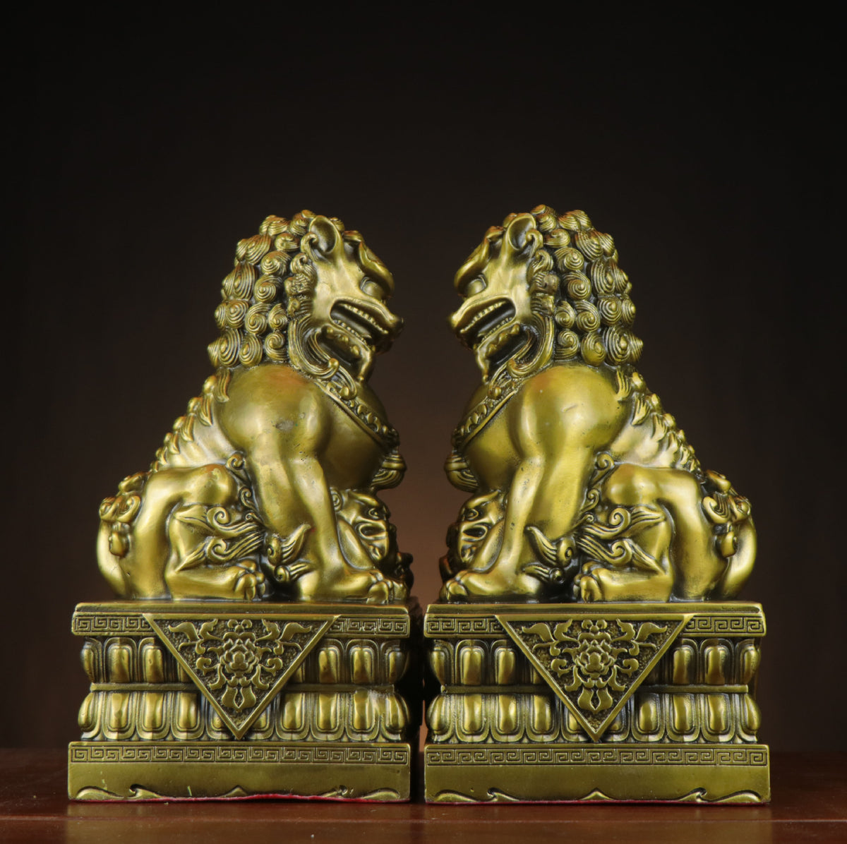 Side view of yellow brass Beijing palace guardian lion pair on lotus-style bases with traditional Chinese door-lion styling