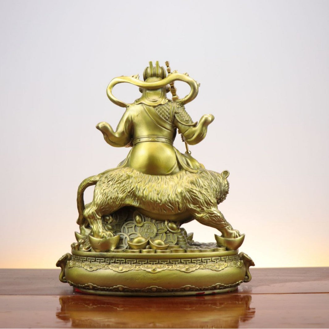 Rear view of Chinese Zhao Gongming Martial God of Wealth copperware sculpture riding a tiger above coins and yuanbao ingots