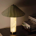 Translucent cloud-stone table lamp with green veined cone shade glowing on a dark console