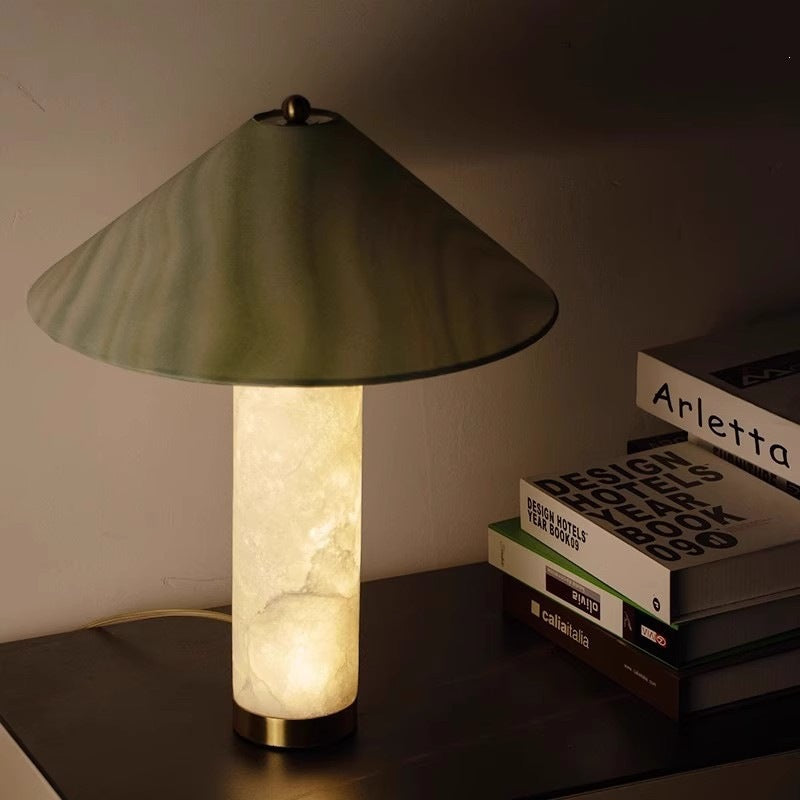 Translucent cloud-stone table lamp with green veined cone shade glowing on a dark console