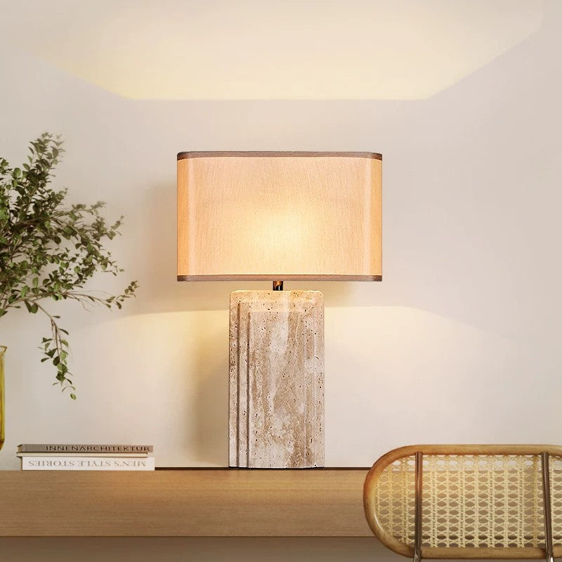 Designer cream travertine table lamp beside cane furniture and greenery