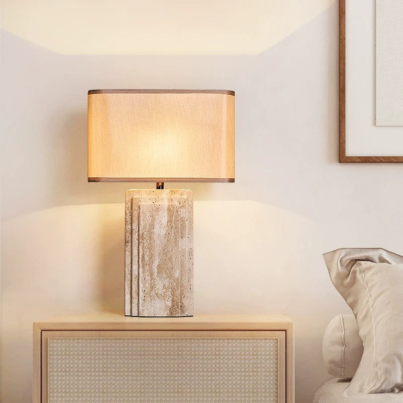 Cream travertine bedside lamp with rectangular fabric shade in a warm bedroom