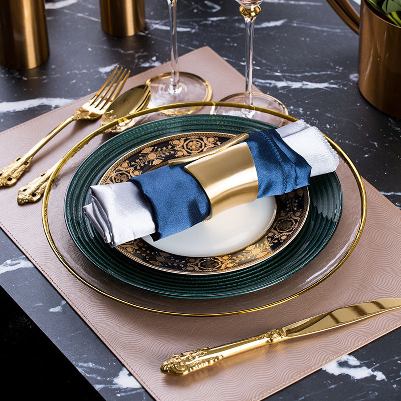 Emerald green and gold luxury table setting with layered dinner plates, gold cutlery and navy napkin