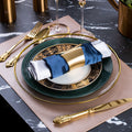 Emerald green and gold luxury table setting with layered dinner plates, gold cutlery and navy napkin