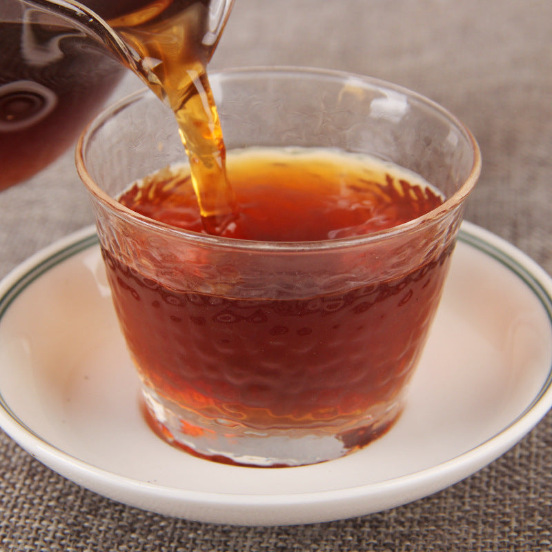 Glutinous rice aroma ripe Pu-erh tea liquor being poured into a glass cup
