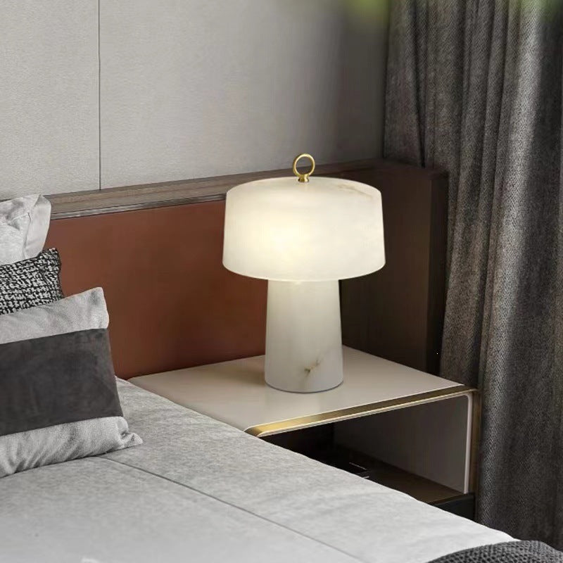 Warm white faux alabaster resin lamp on a contemporary bedside table