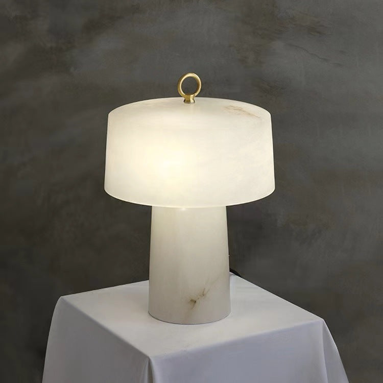 Faux marble resin table lamp displayed on a white pedestal against grey wall