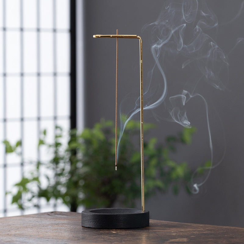 Minimalist hanging incense stick stand with black wood base and gold metal arm