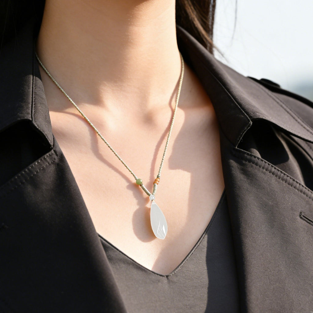 White Hetian jade magnolia pendant necklace worn on black outfit