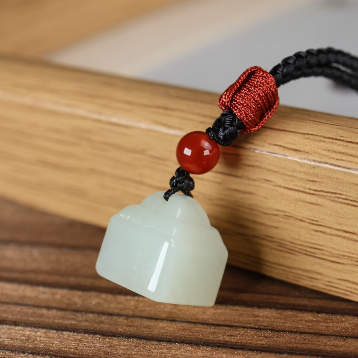 Natural Hetian jade small seal amulet pendant on wooden surface
