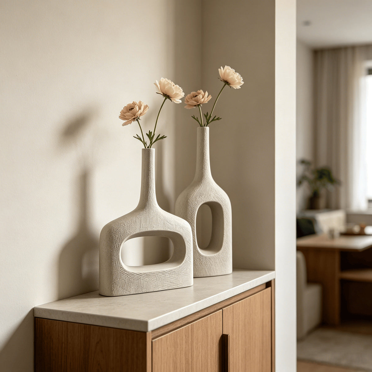 White hollow geometric ceramic vases styled with flowers in a warm minimalist interior