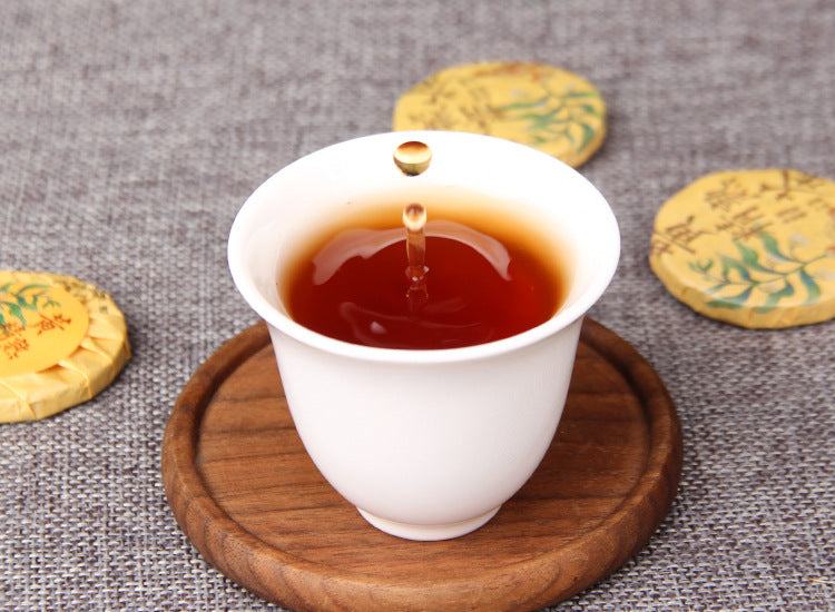 Amber red tea liquor brewed from Huangjing ripe Pu-erh mini cakes