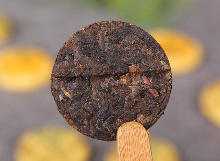 Unwrapped Huangjing ripe Pu-erh mini cake showing compressed fermented tea leaves