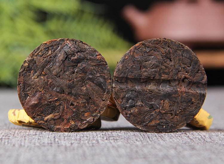 Two unwrapped Huangjing ripe Pu-erh mini compressed tea cakes