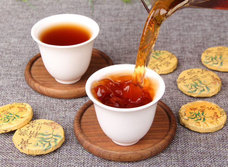 Amber-red Huangjing ripe Pu-erh tea being poured into a tasting cup