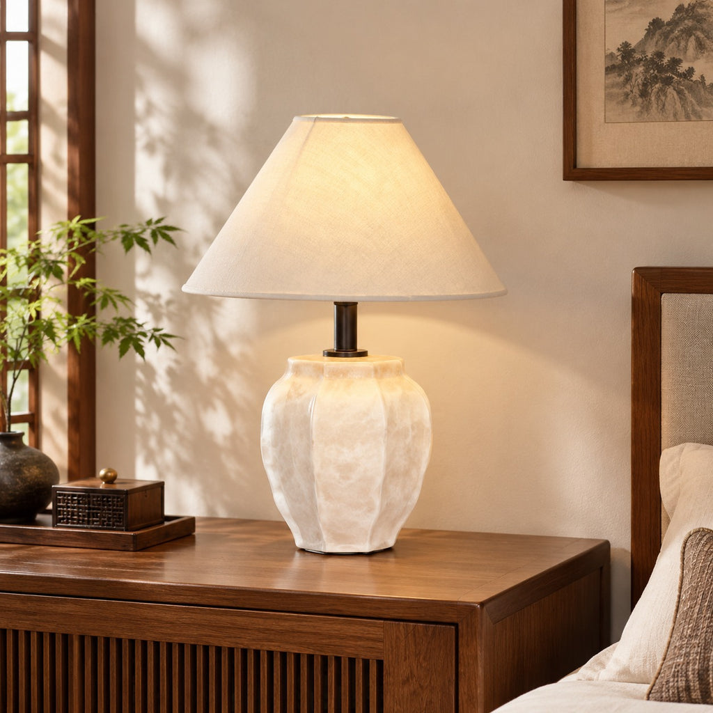 Ivory faceted ceramic jar table lamp with cream fabric shade on a walnut console