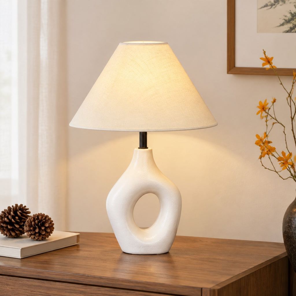 White sculptural cutout ceramic table lamp with warm fabric shade