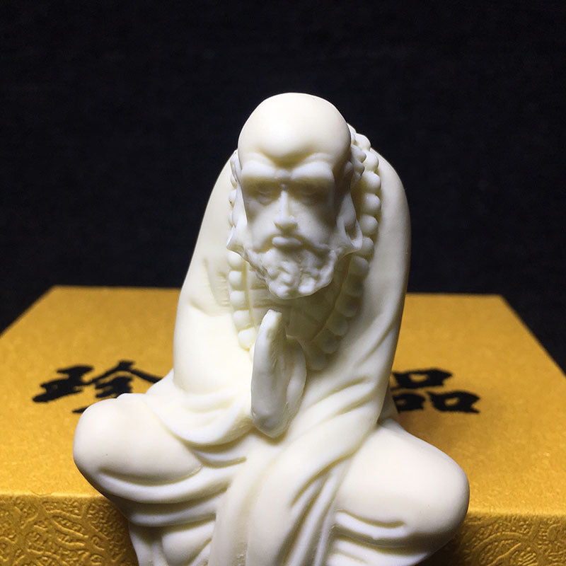Close-up Bodhidharma portrait carved from ivory nut tagua with prayer beads and robe detail