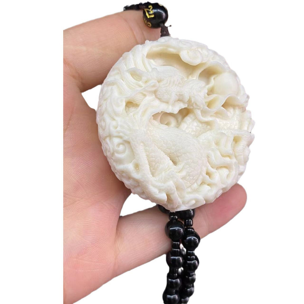 Angled view of ivory nut Dragon and Phoenix Long Feng Cheng Xiang round pendant, 5 cm tagua vegetable ivory Chinese hanging ornament