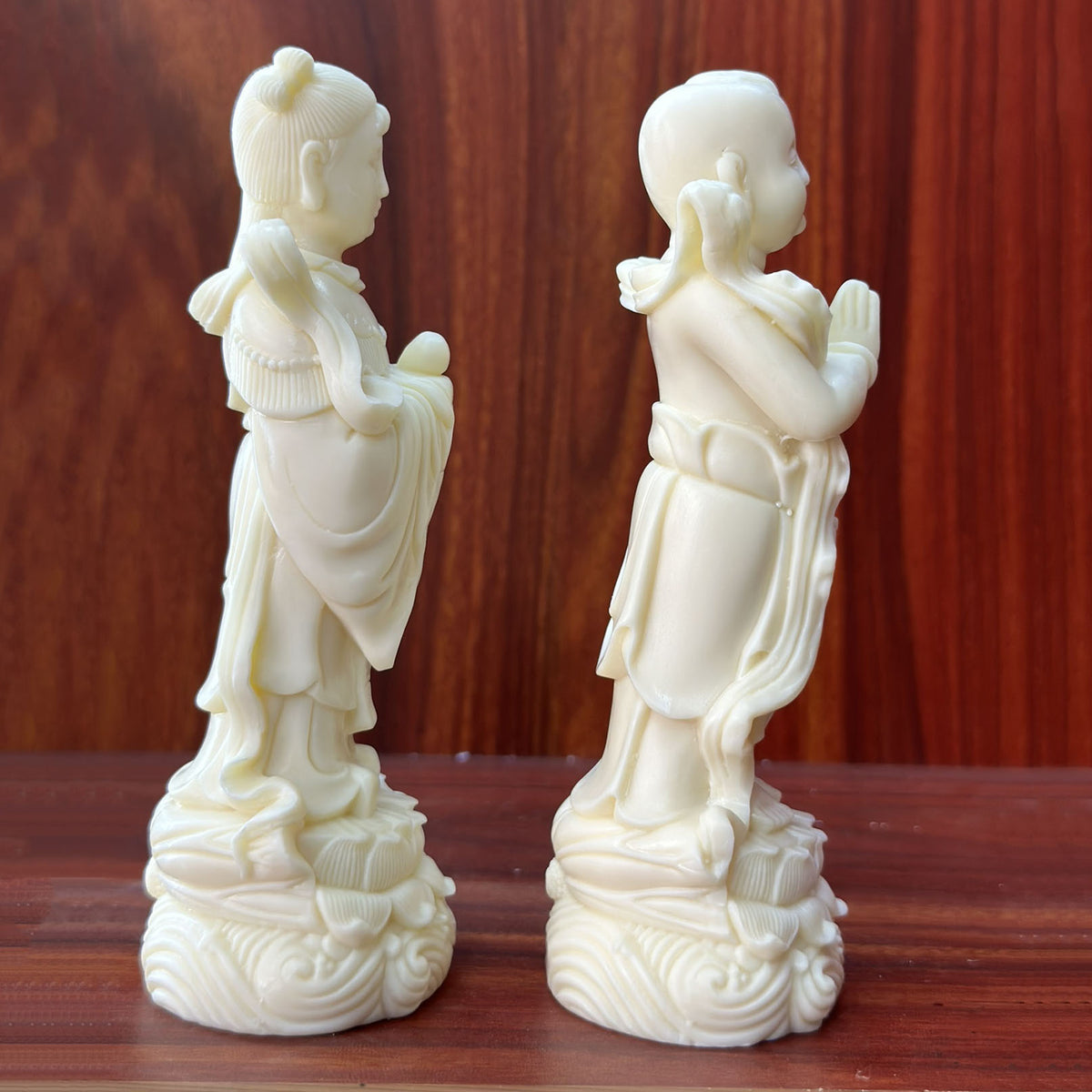 Side profile ivory nut Golden Boy and Jade Girl pair with flowing ribbons and lotus bases, tagua vegetable ivory sculpture