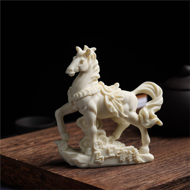 Carved ivory nut horse prosperity ornament displayed on a wooden desk in Chinese decor style