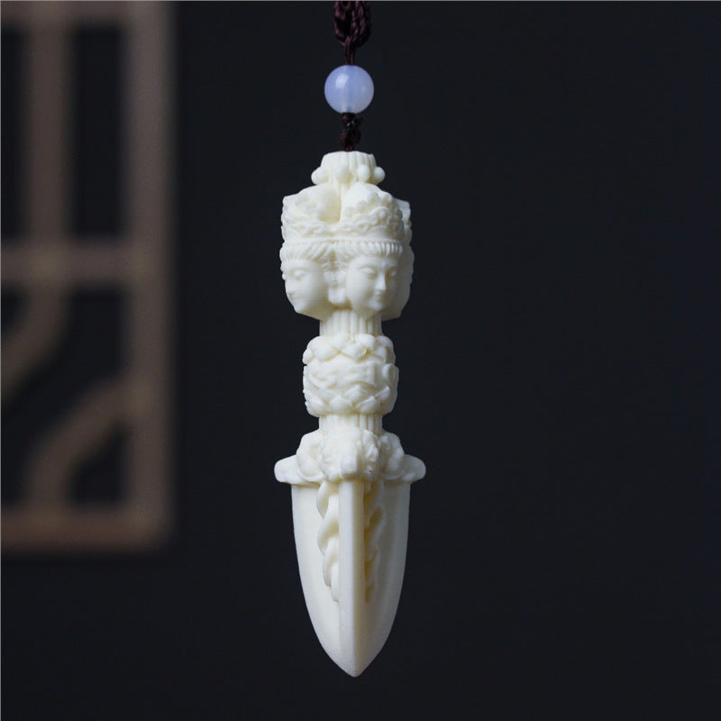 Side view of ivory nut Jiangmo Chu ritual-dagger-inspired hanging carving with multiple carved faces, tagua vegetable ivory pendant approximately 10 cm
