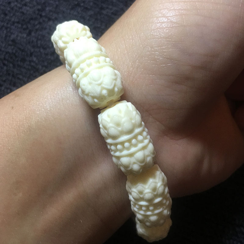 Ivory nut lotus barrel bead bracelet worn on wrist, close-up of carved tagua vegetable ivory lotus barrel beads