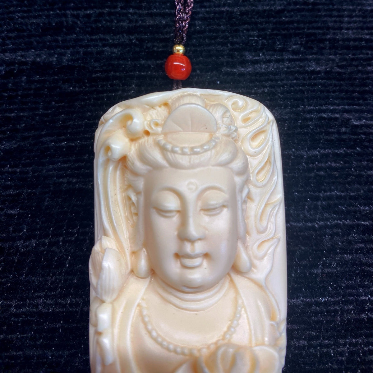 Close-up ivory nut Lotus Guanyin carving with serene face and lotus detail, tagua vegetable ivory pendant