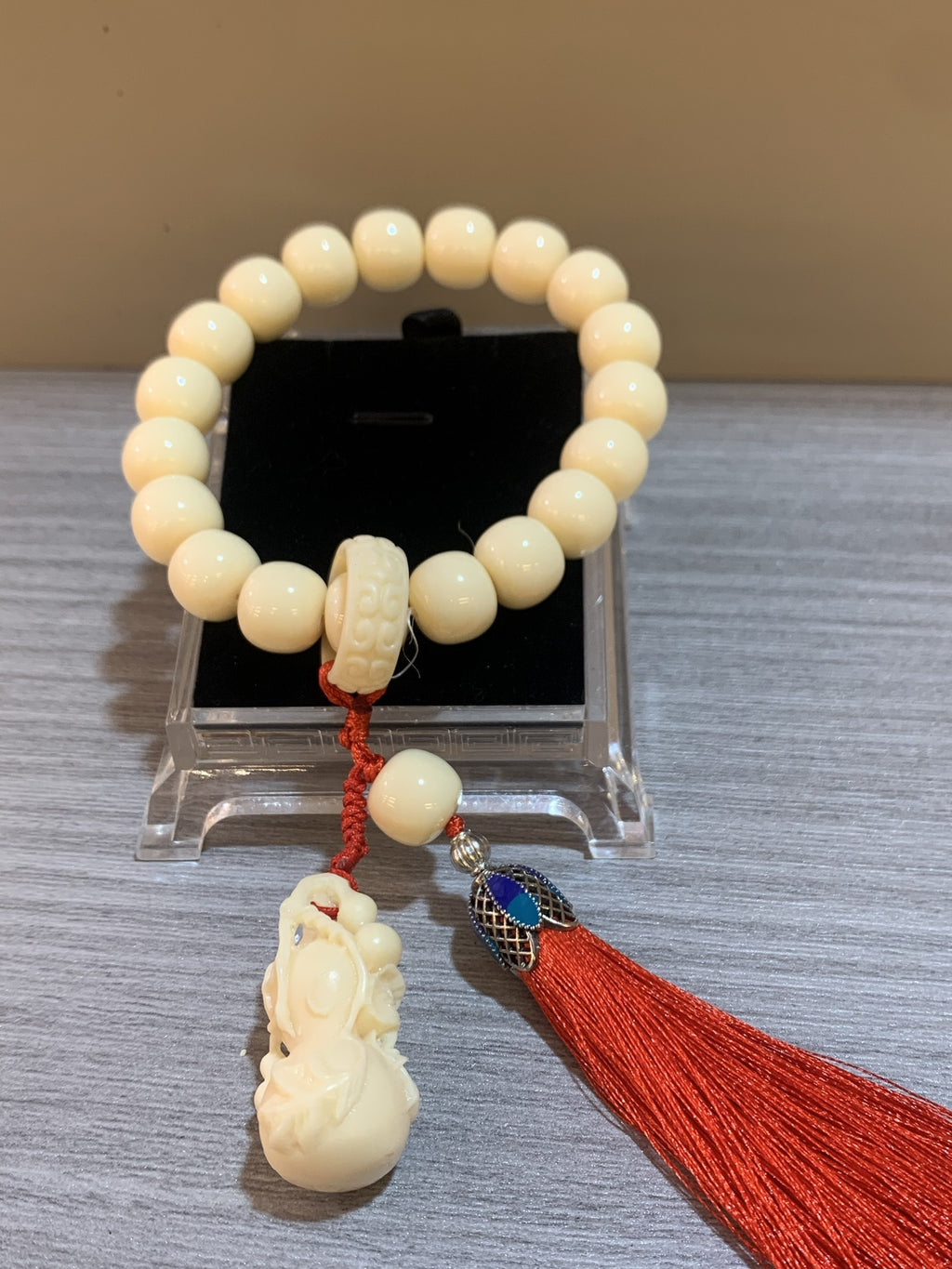 Chinese many blessings ivory nut tagua bracelet displayed with carved pendant and auspicious red tassel