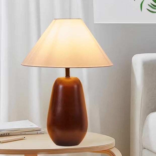 Rounded brown wood table lamp with cream shade used as warm bedside lighting