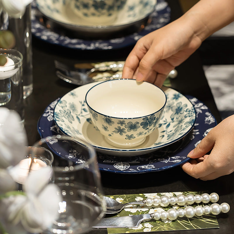 Lantang Weiyang blue floral ceramic footed bowl layered over coordinating plates on a dark dining table
