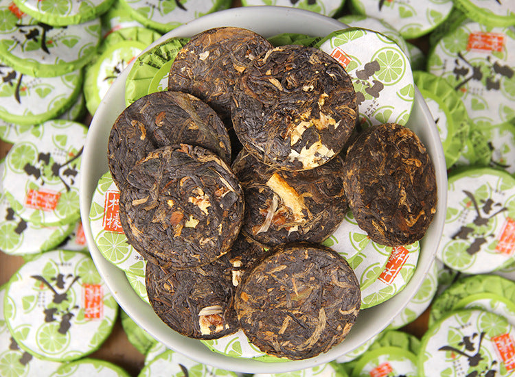 Plate of compressed Yunnan lemon black tea mini cakes with individual green wrappers