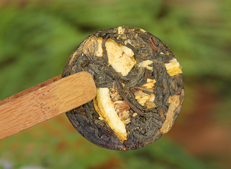 Single Yunnan lemon black tea mini cake showing compressed leaf and citrus pieces