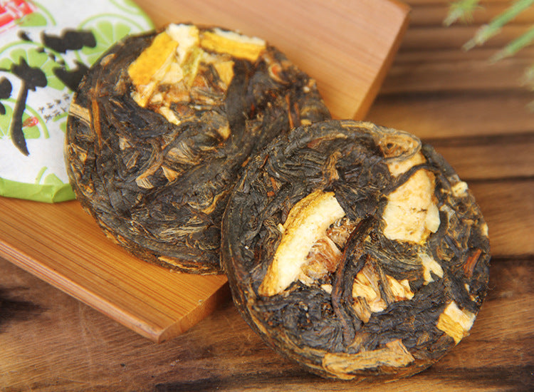 Unwrapped compressed lemon Dianhong black tea mini cakes beside their wrappers