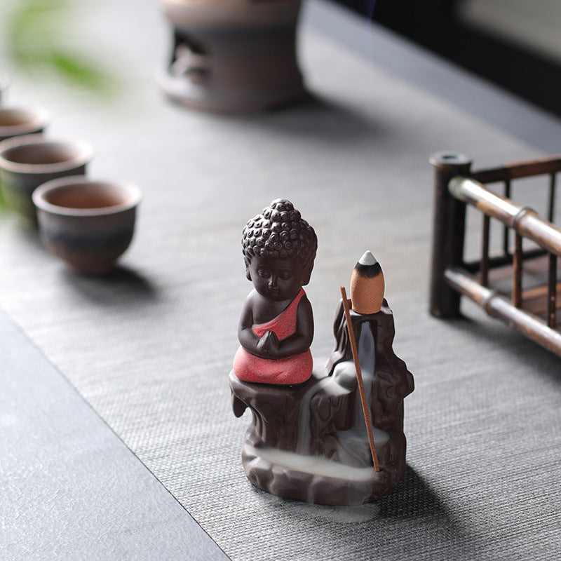 Little Buddha backflow incense burner styled beside tea cups