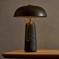 Black dome mushroom table lamp with dark marble sculptural base and warm downward glow