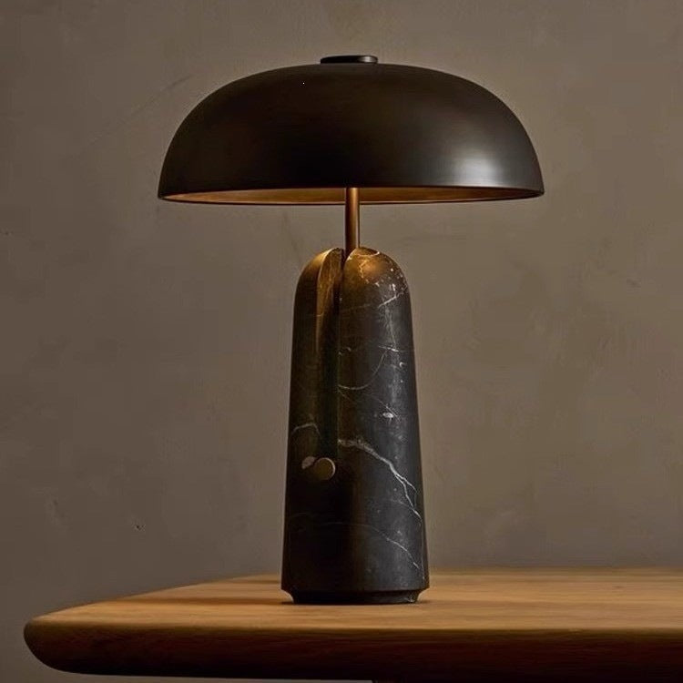 Black dome mushroom table lamp with dark marble sculptural base and warm downward glow