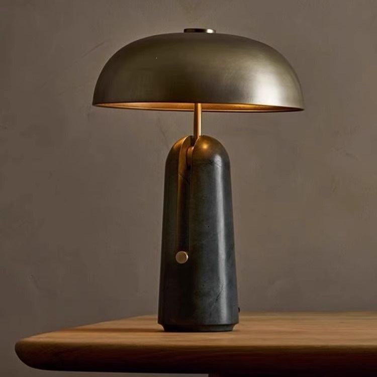 Brushed gold dome table lamp with dark marble base, warm ambient light
