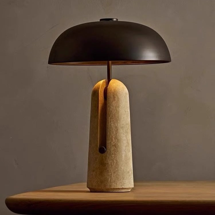 Black dome table lamp with warm beige travertine base, front view