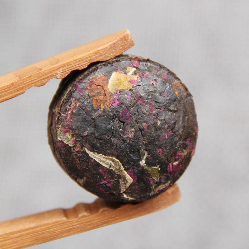 Rose Ripe Pu-erh mini tuocha held with bamboo tea tongs 玫瑰普洱熟茶