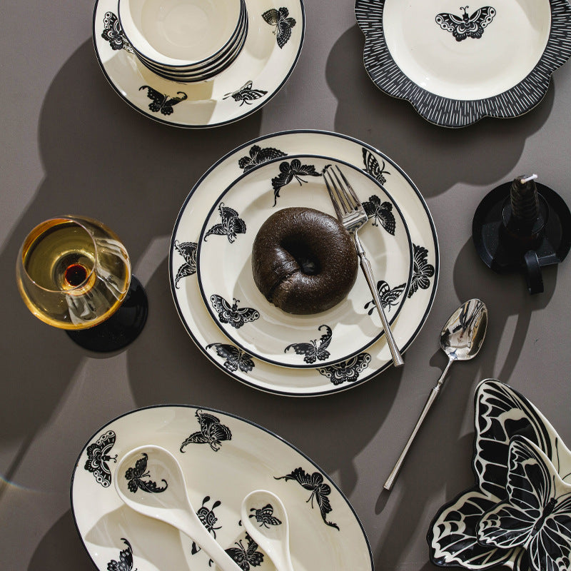 Black and ivory butterfly ceramic plates bowls spoons and serving pieces styled as a modern French vintage table setting