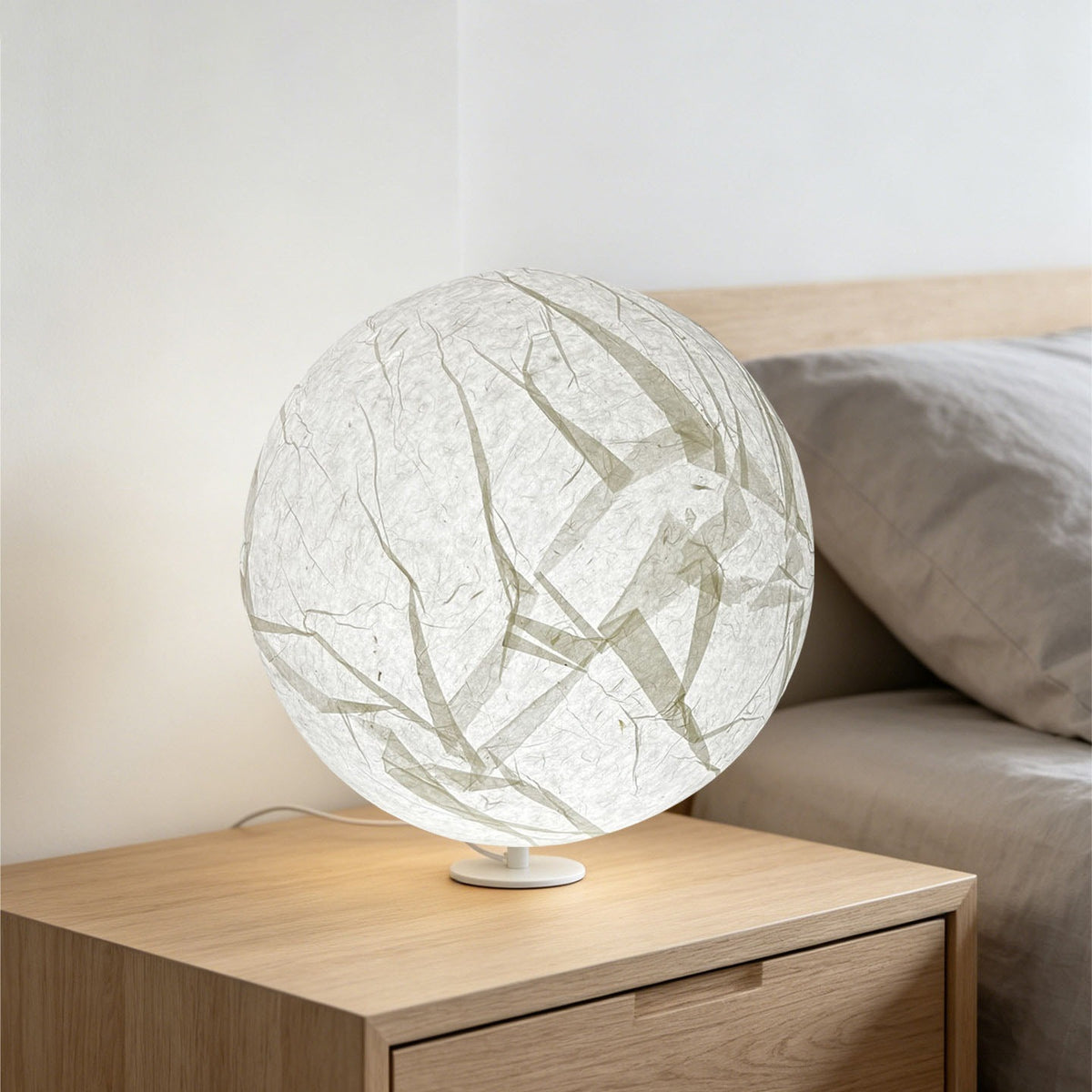Japanese paper moon table lamp on a light wood bedside table