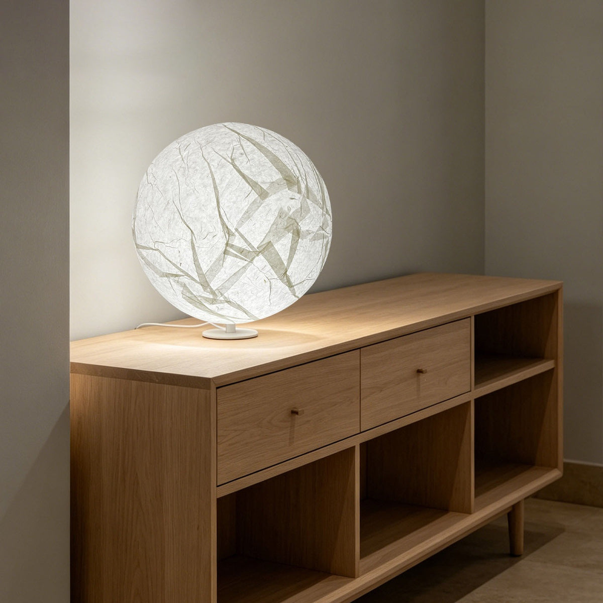 White paper moon sphere table lamp on a natural wood console